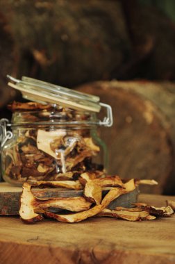 Ahşap bir arka planda cam bir kavanozda kurutulmuş mantar. Dondurulmuş sebzeler. Kurutulmuş baharatlar sağlıklı yiyecekler. Baharatlar.