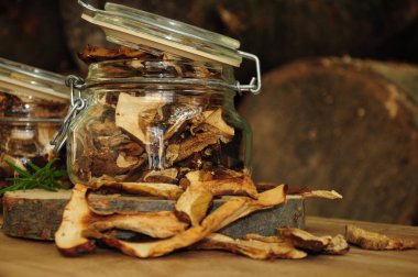 Ahşap bir arka planda cam bir kavanozda kurutulmuş mantar. Dondurulmuş sebzeler. Kurutulmuş baharatlar sağlıklı yiyecekler. Baharatlar.