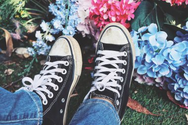 Siyah spor ayakkabıların ve yapay çiçeklerin selfie 'si.