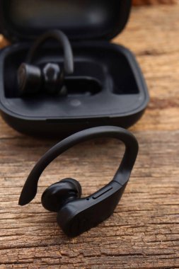 Ahşap arka planda siyah kablosuz bluetooth kulaklıklar