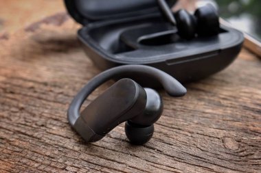 Ahşap arka planda siyah kablosuz bluetooth kulaklıklar
