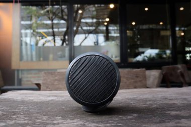 Kahverengi ahşap arkaplan doku masasında siyah bluetooth hoparlör sesi