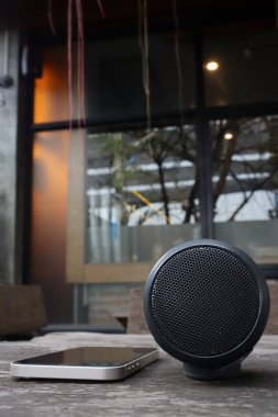 Kahverengi ahşap arka planda bluetooth hoparlörü ve akıllı telefon