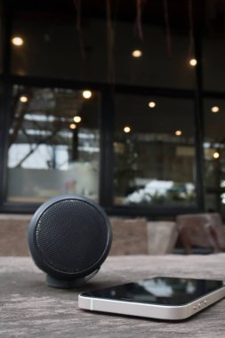 Kahverengi ahşap arka planda bluetooth hoparlörü ve akıllı telefon