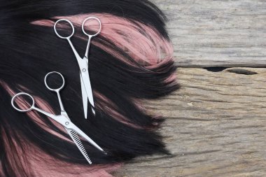 Hair cutting shears and black pink hair on brown wood table