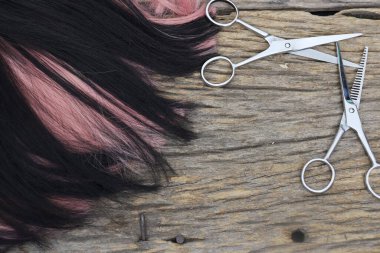 Hair cutting shears and black pink hair on brown wood table
