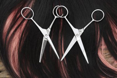 Hair cutting shears and black pink hair on brown wood table