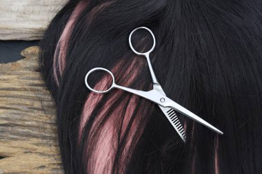 Hair cutting shears and black pink hair on brown wood table