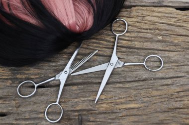 Hair cutting shears and black pink hair on brown wood table