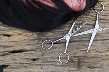 Hair cutting shears and black pink hair on brown wood table