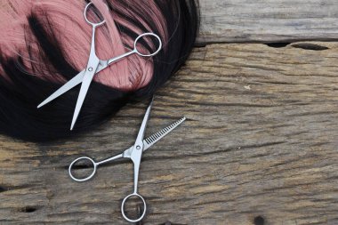 Hair cutting shears and black pink hair on brown wood table