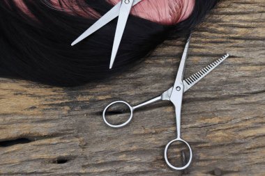 Hair cutting shears and black pink hair on brown wood table