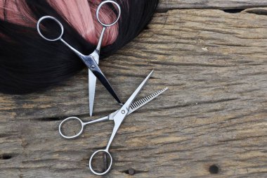 Hair cutting shears and black pink hair on brown wood table
