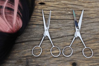Hair cutting shears and black pink hair on brown wood table