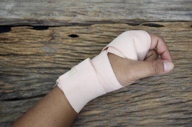 Medical elastic bandage roll and hand on wood table background texture