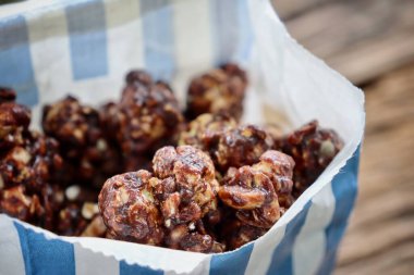 Chocolate covered popcorn and paper bag on wood table