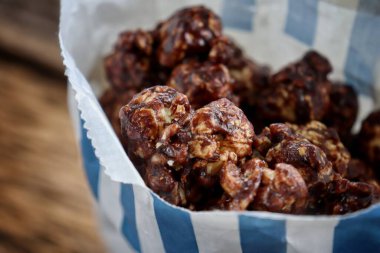 Chocolate covered popcorn and paper bag on wood table