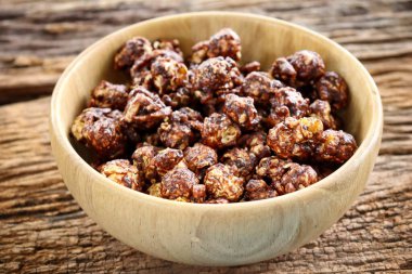 Chocolate covered popcorn on wood bowl on brown table