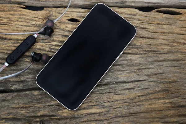 Smart phone and earphone music on brown wood table