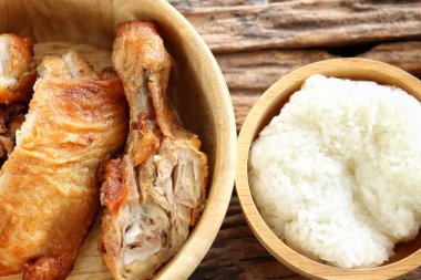 Ahşap kasede kızarmış tavuk ve ahşap masa arkasında yapışkan pirinç.