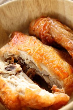 Kahverengi masa arkasında kızarmış tavuk ve ahşap kase.