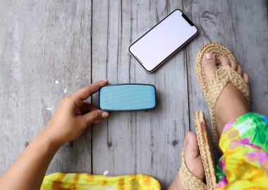 Akıllı telefon kullanan ve bluetooth hoparlörü kullanan bir kadın.