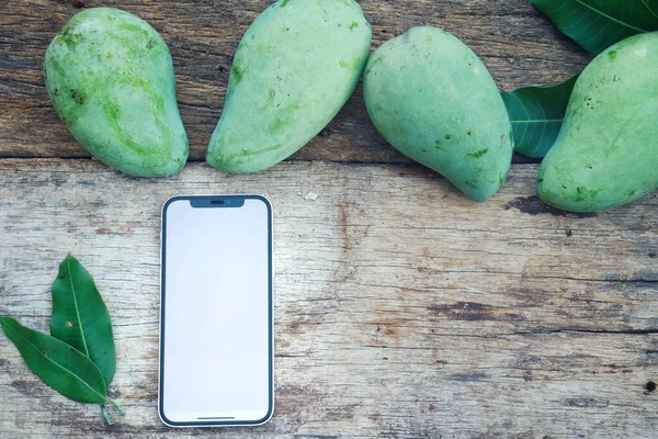 Smart Telefon Och Grön Mango Tropisk Frukt Trä Bakgrund — Stockfoto