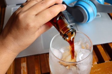 Ev konseptinden kalma kulaklıkla cam ve deftere kola dökmek.