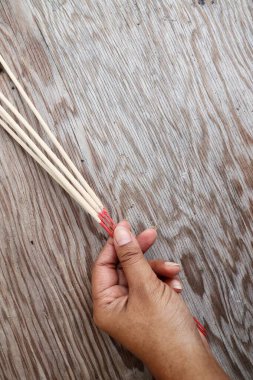 Kahverengi kızılderili tütsü aromalı çubuklar ve kahverengi ahşap masa zemininde el.