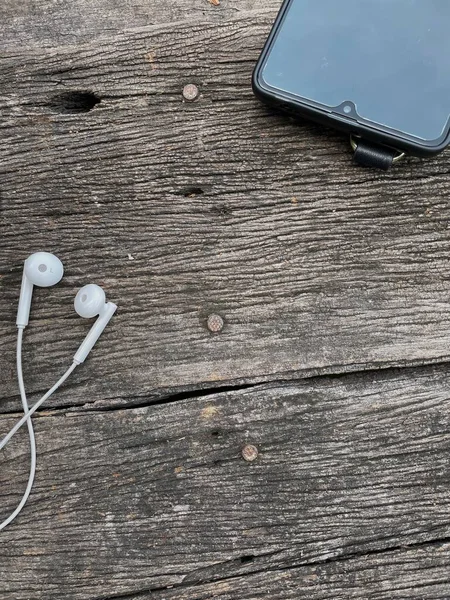 Close up of white earphone and smart phone on wood table background