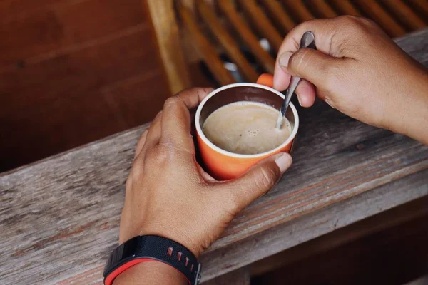 Hot coffee with milk on a cup and hands