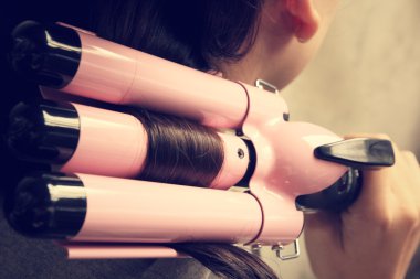 Saç düzleştirici kullanan kadın