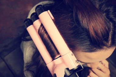 Saç düzleştirici kullanan kadın