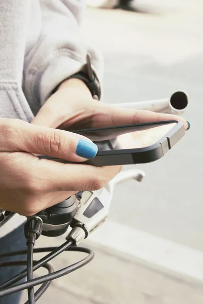 Woman using smart phone on bike — Stock Photo, Image