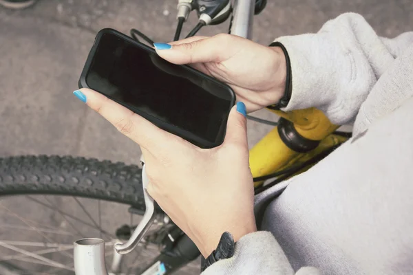 Woman using smart phone on bike — Stock Photo, Image