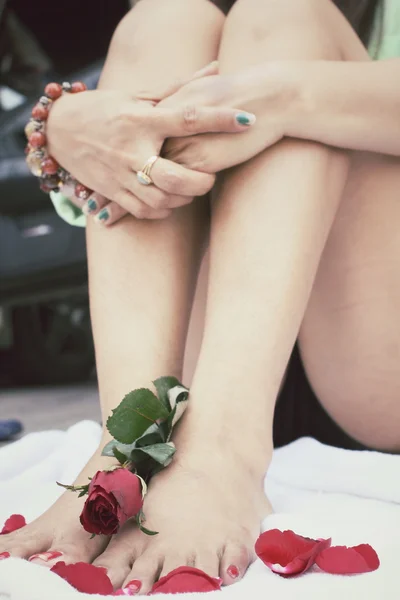 Vrouw voet met rode roos — Stockfoto