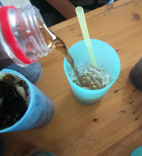 Derramando um copo de cola com cubos de gelo — Fotografia de Stock