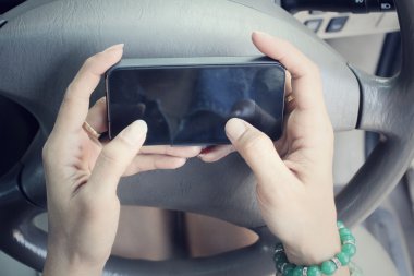 Arabada akıllı telefon kullanan kadın.
