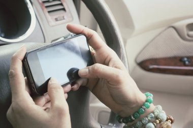 Arabada akıllı telefon kullanan kadın.