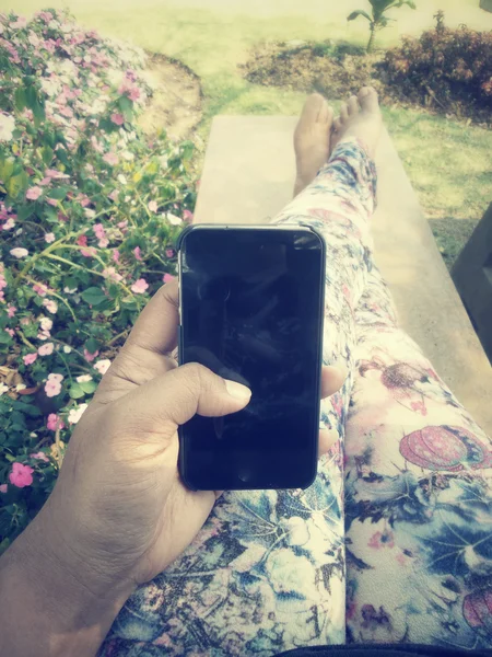 Kvinna med smart telefon i trädgården — Stockfoto