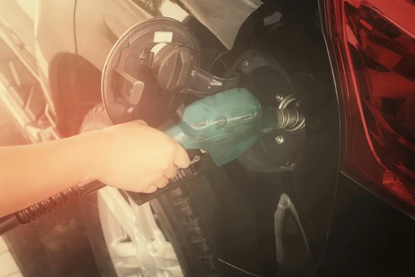 Hand refilling the car with fuel.