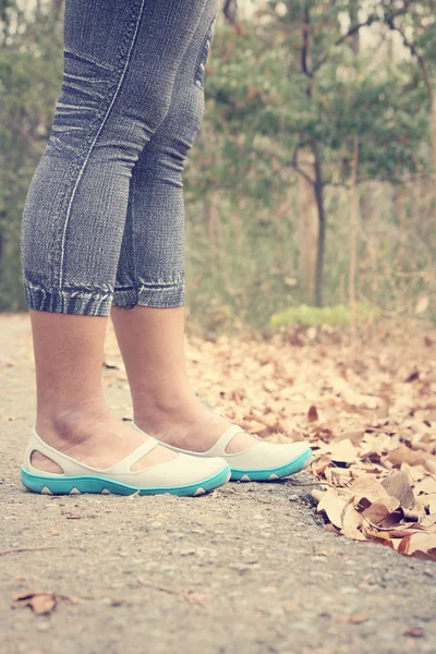 Mulher andando com sapatos nas folhas de outono — Fotografia de Stock