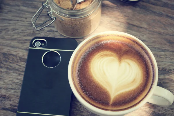 Винтажный кофе с латте и смартфоном — стоковое фото