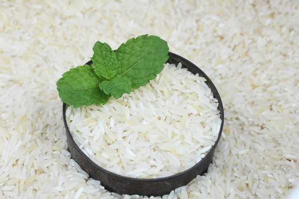 Grano de arroz crudo con hoja de menta — Foto de Stock