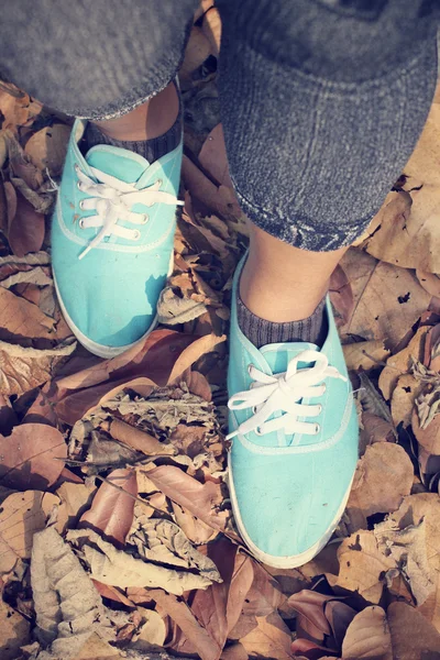 Mulher andando com sapatos nas folhas de outono — Fotografia de Stock