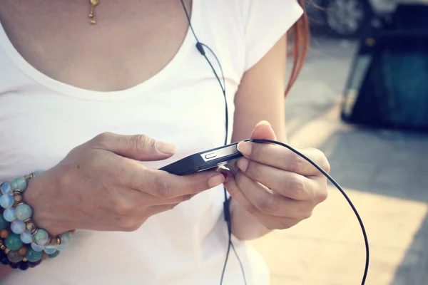 Kvinna lyssna på musik på hörluren med smart telefon — Stockfoto