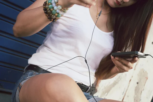 Kvinna lyssna på musik på hörluren med smart telefon — Stockfoto