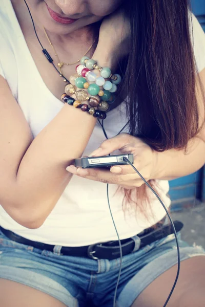 Mulher ouvindo música no fone de ouvido com telefone inteligente — Fotografia de Stock