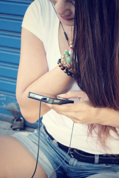 Kvinna lyssna på musik på hörluren med smart telefon — Stockfoto