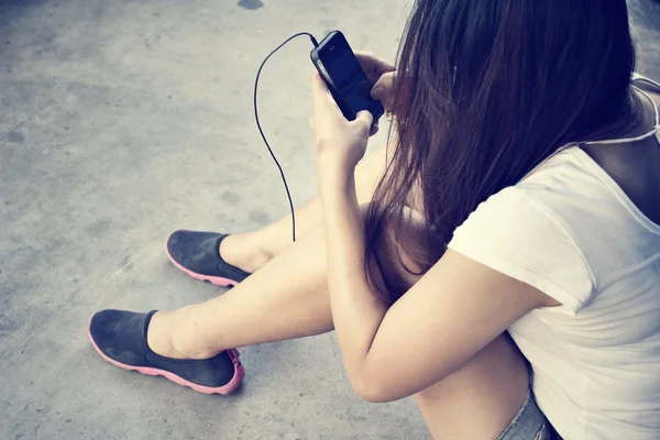 Mulher ouvindo música no fone de ouvido com telefone inteligente — Fotografia de Stock